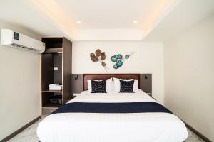 ein Schlafzimmer mit einem großen weißen Bett mit blauen Kissen in der Unterkunft RoomQuest Sukhumvit36 BTS Thonglor in Bangkok