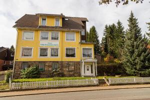 una casa gialla sul lato di una strada di Ski und Biker Hotel Villa Sonnenschein Braunlage am Wurmberg a Braunlage