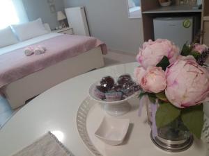 a white table with a vase of pink flowers on it at Perfect Location in Tríkala