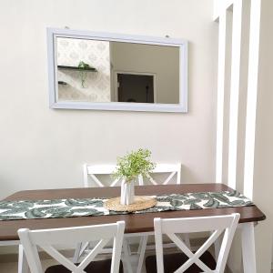 uma mesa de jantar com 2 cadeiras brancas e um espelho em Villa Kayana F15 - 2 Bedroom Full AC em Karangploso