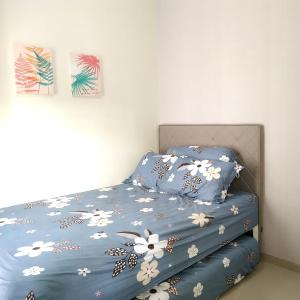 uma cama com lençóis azuis com flores brancas em Villa Kayana F15 - 2 Bedroom Full AC em Karangploso