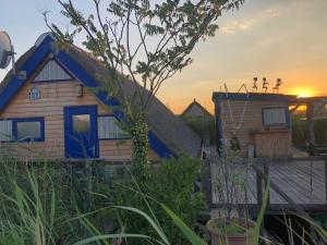 a house with a blue roof with the sunset in the background at Pfahlbau Neusiedlersee - Waterfront - erste Reihe in Rust