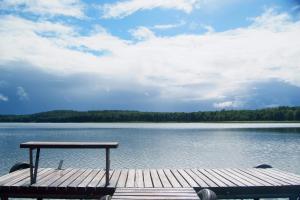 a picnic table sitting on a dock on a lake at Letnisko Zalesie in Rentyny
