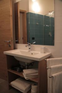uma casa de banho com lavatório, espelho e toalhas em MOUNTAIN RESORT Appartamenti em Commezzadura