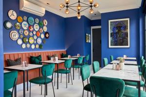 a dining room with blue walls and tables and green chairs at Pineapple House Boutique Hotel in Cape Town