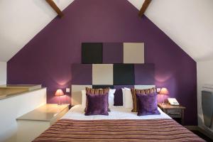 a bedroom with a large bed with purple walls at The Deddington Arms in Banbury