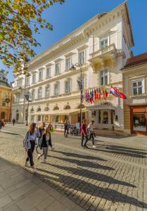 Un gruppo di persone che camminano davanti a un edificio di Hotel Imparatul Romanilor a Sibiu