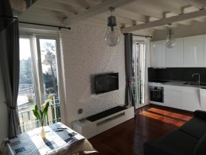 a kitchen with a living room with a tv and a table at House Orizzonte - Casa Bianca in Genoa