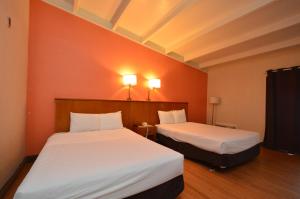2 Betten in einem Zimmer mit orangefarbenen Wänden in der Unterkunft Clearwater Hotel in Clearwater