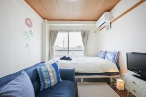 a living room with a blue couch and a bed at Sun white Gyoutoku 202 in Urayasu