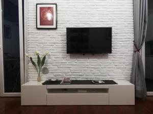 uma sala de estar com televisão numa parede de tijolos brancos em House Orizzonte - Casa Bianca em Gênova