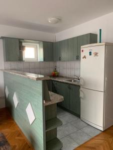 een keuken met groene kasten en een witte koelkast bij Apartman MADAPE in Sesvete