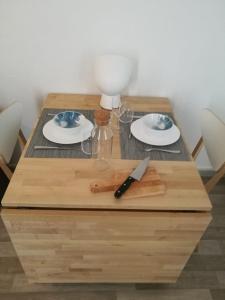 a wooden table with a knife and plates on it at Le Cocon de Cordeliers in Lyon