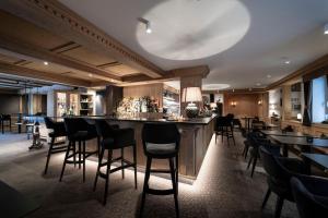 bar w restauracji z czarnymi stołkami barowymi w obiekcie Hotel Acadia - Adults Mountain Home w mieście Selva di Val Gardena