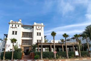 a white building with palm trees in front of it at Borjs Hotel Suites & Spa in Agadir