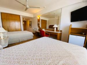 a hotel room with two beds and a flat screen tv at Hotel Garden in Rosario