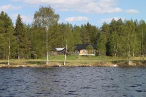 una cabaña a orillas de un lago con árboles en Niemen Lomat, en Kuusamo