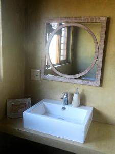 La salle de bains est pourvue d'un lavabo blanc et d'un miroir. dans l'établissement Mkhiweni Villa at Dombeya Wildlife Estate, à Mbabane
