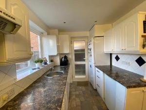 uma cozinha com armários brancos e um lavatório em Lovely Homes em Aylesbury