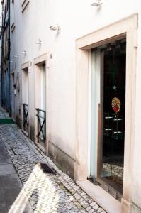 eine Kopfsteinpflasterstraße mit einem weißen Gebäude mit Fenstern in der Unterkunft Residencia Coimbra in Coimbra