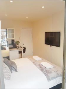 a bedroom with a white bed with a flat screen tv at The 55 in Enfield