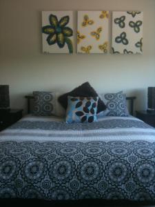 
a bed with a blue and white comforter and pillows at Denman Serviced Apartments in Denman
