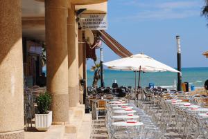 a row of tables with chairs and umbrellas on the beach at la mata aqua nature in La Mata