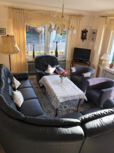 a living room with a black leather couch and a table at Haus Kottenborn am Nürburgring in Kottenborn