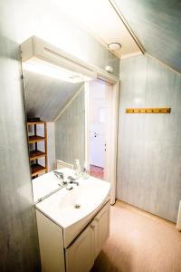 La salle de bains est pourvue d'un lavabo blanc et d'un miroir. dans l'établissement Utsira Overnatting - Fyrvokterboliger, à Utsira