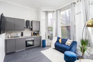 uma sala de estar com um sofá azul e uma cozinha em Kensington Modern Apartment em Londres
