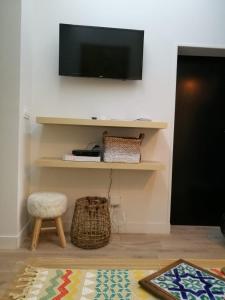 a living room with a tv on the wall and a stool at Le Cocon du Gourguillon - Vieux Lyon in Lyon