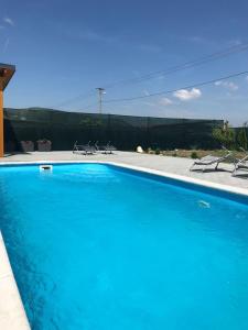 a large blue swimming pool with chairs and a fence at Apartmány Milovice in Milovice