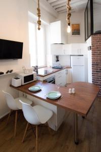Il comprend une cuisine équipée d'une table avec deux chaises et d'un four micro-ondes. dans l'établissement Le Ferratière - Moderne industriel du Vieux Lyon, à Lyon