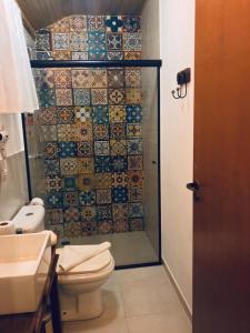y baño con aseo y ducha con azulejos. en Pousada de Charme Emirados en Ilhabela