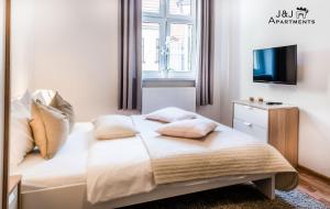um quarto com uma cama com almofadas e uma televisão em J&J Apartments, Szeroka 25 Apartament 7 em Toruń