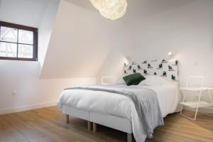 a white bedroom with a white bed and a window at Les apparts du marché in Obernai