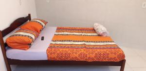 a bed with an orange blanket and pillows on it at Apartamentos de Férias por Temporada Martim De Sá in Caraguatatuba
