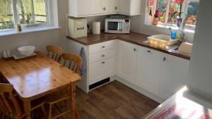 a kitchen with a wooden table and a microwave at Hayloft Cottage - Dog Friendly With Private Garden in Sidmouth