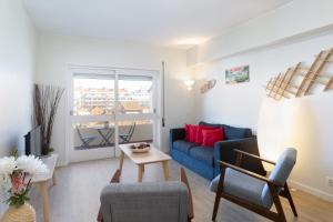 a living room with a blue couch and a table at Trendy Bright Flats with Jacuzzi - 5 min Beach in Matosinhos