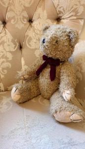 a brown teddy bear sitting on a white couch at Station House, cafe, bar and rooms in South Brent