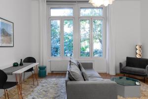 a living room with a couch and a table and windows at The Suite Hotel Fabric in Frankfurt