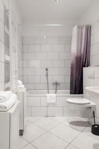 a white bathroom with a tub and a toilet and a sink at The Suite Hotel Fabric in Frankfurt