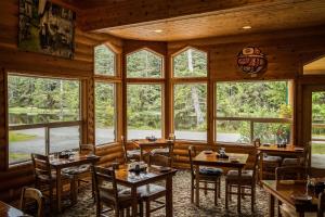 a restaurant with tables and chairs in a room with windows at Haida House at Tllaal in Tlell