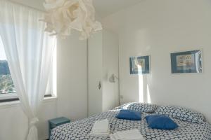 ein Schlafzimmer mit einem Bett mit blauen Kissen und einem Fenster in der Unterkunft Cosy Apartment by PortofinoVip in Rapallo
