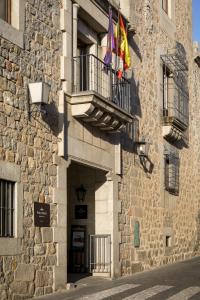 a stone building with two flags on a balcony at Parador de Ávila in Ávila