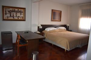 a bedroom with a bed and a desk and a desk at Hotel Cervantes in Mendoza