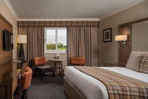 a hotel room with a bed and a table and a window at Radstone Hotel in Larkhall