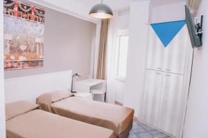 Habitación pequeña con 2 camas y TV. en Hotel Piccolo Sogno, en Pompeya