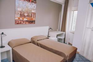 ポンペイにあるホテル ピッコロ ソーニョのベッド2台、テーブル、窓が備わる客室です。