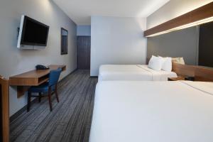 a hotel room with two beds and a desk and a television at Baymont by Wyndham Las Vegas South Strip in Las Vegas